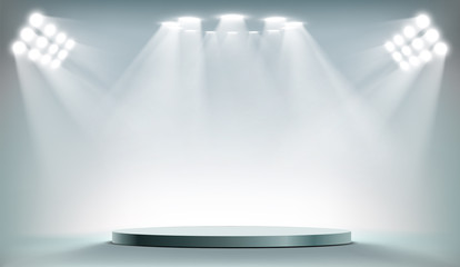 Round podium illuminated by searchlights.