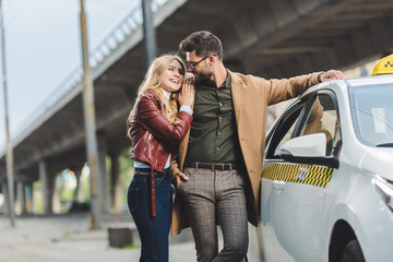 Wall Mural - beautiful happy young couple smiling each other while standing together in taxi car