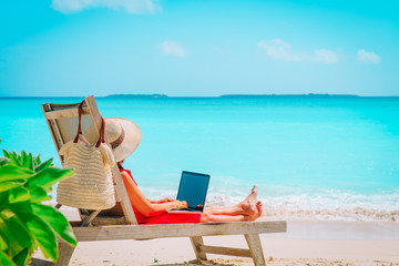 Wall Mural - remote work concept -young woman with laptop on beach