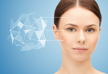 beauty, science and future technology concept - portrait of beautiful woman with low poly shape projection pointing to face over blue background