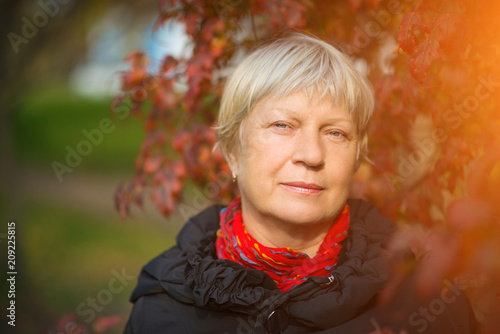 Poster Portrait of a beautiful middle-aged woman outdoors with sunlight.