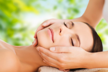 Wall Mural - wellness, spa and beauty concept - close up of beautiful woman having face massage over green natural background