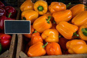 close up view of red and yellow bell peppers with blank signobard