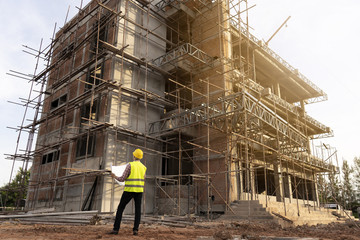 Young engineer working with  blueprint  at  a construction site. 