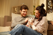 Pets, Hygge And People Concept - Happy Couple With Cat At Home