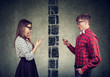 © Feodora - Shocked couple man and woman separated by wall texting each other on mobile phone