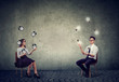 © Feodora - Business man juggling with idea light bulbs with business woman managing time and efficiency