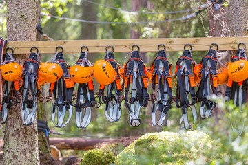 Climbing gear equipment - orange helmet harness zip line safety equipment hanging on a board. Tourist summer time adventure park family and company team building concept for extreme recreation sports