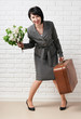 © soleg - business woman dressed in a gray suit with suitcase stay in front of a white wall