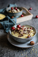 Wall Mural - Millet porridge topped with chocolate pieces, hazelnuts, almond slices and cherry