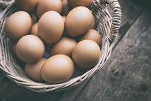 Fresh Eggs In Basket On Old Wooden Background