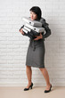 © soleg - business woman with folder, dressed in a gray suit poses in front of a white wall