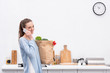© LIGHTFIELD STUDIOS - happy adult woman with paper bag talking by phone at kitchen