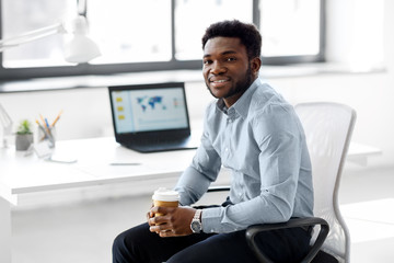 Wall Mural - business and people concept - african american businessman with coffee sitting at office table