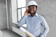 © Syda Productions - architecture, construction business and people concept - african american architect in helmet with blueprint calling on smartphone