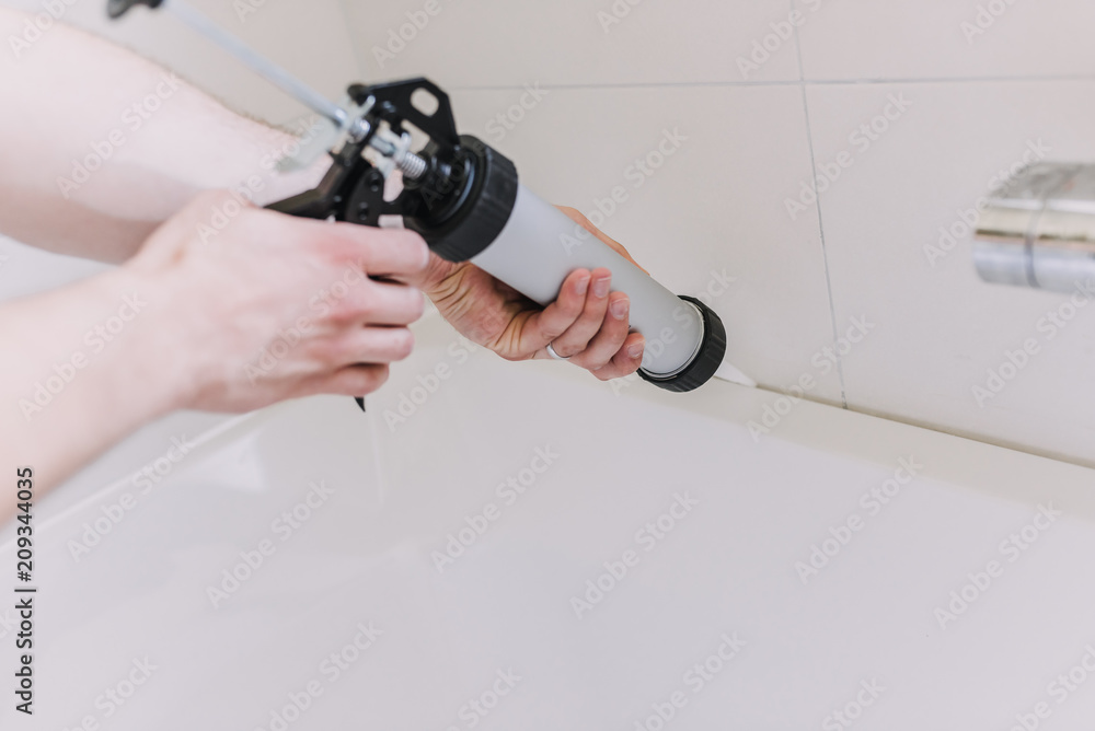 hands of man putting a silicon with a silicon tube in bathroom - obrazy, fototapety, plakaty 