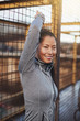 © Flamingo Images - Asian woman in sportswear leaning against a mesh wall outdoors