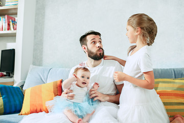 Wall Mural - The happy father and his baby daughters at home