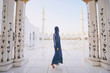 Traveling by Unated Arabic Emirates. Woman in traditional abaya standing in the Sheikh Zayed Grand Mosque, famous Abu Dhabi sightseeing.