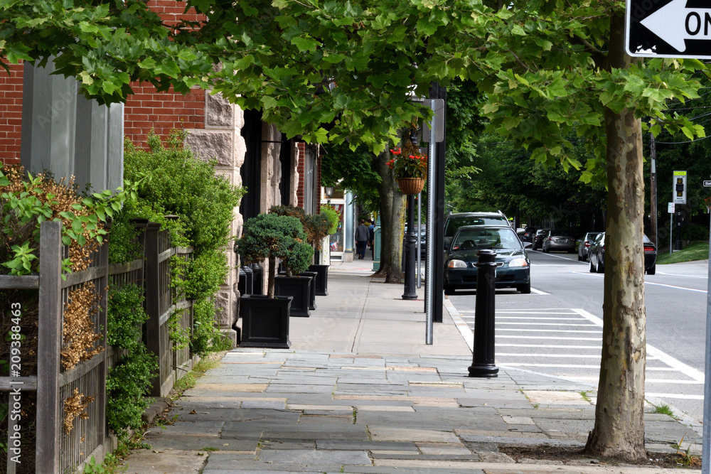 Quiet street and sidewalk with few cars and no people showing a 