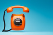 © BigBlueStudio - Old orange telephone rings with handset off.