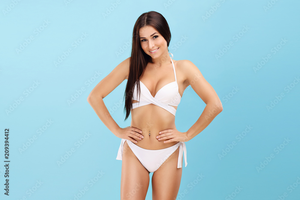 Sexy woman in bikini posing against blue background - obrazy, fototapety, plakaty 