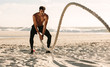 © Jacob Lund - Man doing fitness training at the beach using battling rope