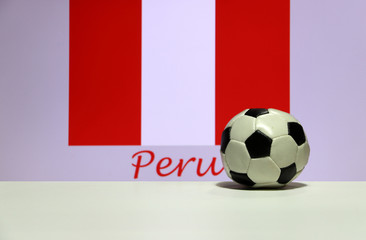 Small football on the white floor and Peruvian nation flag with the text of Peru background. The concept of sport.