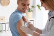 © New Africa - Doctor vaccinating male patient in clinic