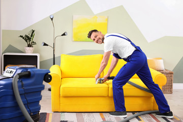 Canvas Print - Dry cleaning worker removing dirt from sofa indoors