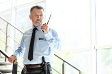 Male Security Guard Using Portable Radio Transmitter Indoors