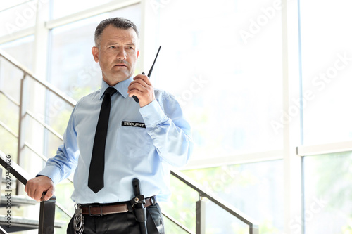 Fotomural Male security guard using portable radio transmitter indoors