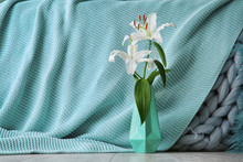 Vase With Beautiful Lilies And Mint Cloth On Background