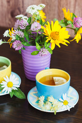 Cups of herbal tea with camomile and mint leaves on the wooden background