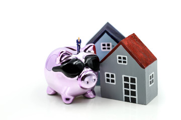 Miniature people : Businessman standing with Piggy bank  with house and stack of coins,Saving to buy a house, real estate or home savings concept.