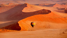 Hot Air Balloon In Flight Against Orange Sand Dunes In Sossusvlei Namibia