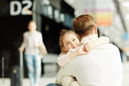 Fotomural Happy little girl embracing her dad in airport lounge after arrival with mother