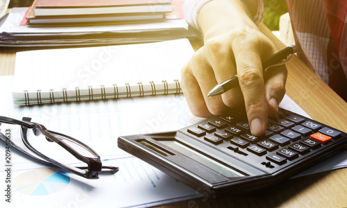 Plakaty do biura rachunkowego hand-use-calculator-on-the-office-desk-investment-and-property-for-concept