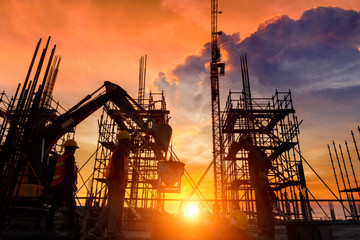 Silhouette crane construction equipment,Industrial construction cranes and building over amazing sunset sky abstract background,dramatic clouds behind crane in the evening.