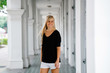 © Danon - Portrait of a young and beautiful blonde exchange student standing in the corridor of her campus. She is wearing comfortable clothes and smiling as she looks around the place.