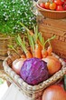Fresh, raw vegetables for cooking:a colorful red cabbage with carrots and onions in a basket with flowers and tomatoes background. Selective focus.