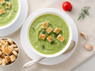 Wall Mural - Two large white bowl with vegetable green cream soup of broccoli, zucchini, green peas on white background, top view