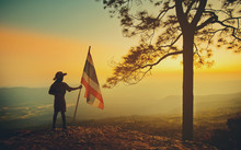 Silhouette Scouts With The Thai Flag Stand On A Cliff At Sunrise.