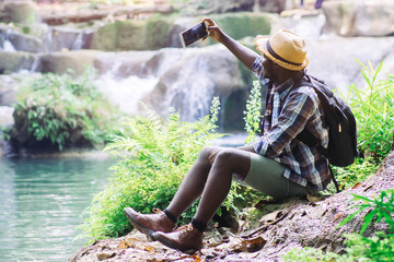 Wall Mural - African Man Traveller with backpack selfie with happy in the green natural background.