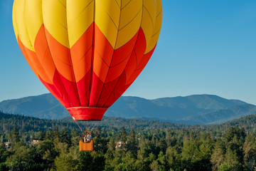 hot air balloon on beautiful sunny morning over wooded hills