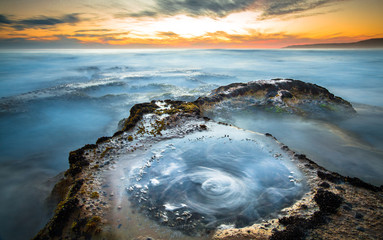 Wall Mural - Long exposure of ocean waves flowing over rocky tidepools at sunset on Johanna Beach in the Great Otway National Park, Victoria, Australia.