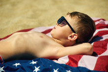 Boy Sunbathing On The Beach .