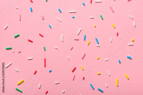 colorful sprinkles over pink background, decoration for cake and bakery