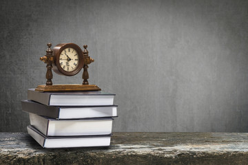 Back to school education concept with clock on book on black chalkboard