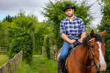 Fototapeta Konie - Handsome cowboy, horse rider on saddle, horseback and boots